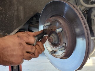 Auto mechanic changing brake disc on a car, closeup of photo