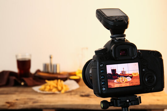 Tasty french fries with cola on display of professional photo camera in studio