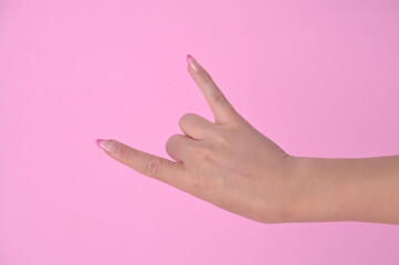 mão feminina com alongamento em fibra de vidro nas unhas fazendo sinal simbolo