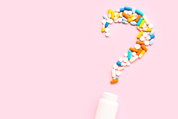 Question mark made of different pills and jar on pink background