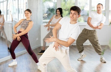 Young guys and girls in sportswear performing hip hop at group dance class