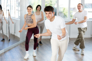Group of young men and women rehearsing jazz funk dance in studio
