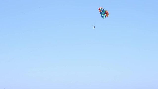 Man flying a paraplane in the blue sky.