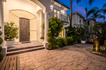 Naklejka premium Illuminated stone path and stairs leading to a house entrance at sunset