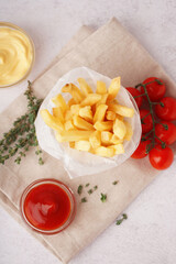 Glass with tasty french fries and sauces on white background