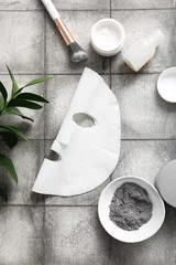Poster Facial sheet mask with different cosmetic products and leaves on grey tile background © Pixel-Shot