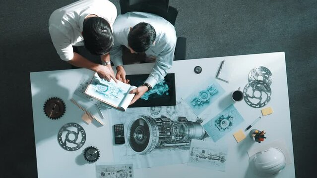 Top down aerial view of manager sitting while answer question about jet engine. Professional engineer looking at turbine engine or electronic generator while colleague asking question. Alimentation.