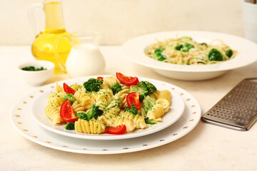 Plates of tasty pasta with broccoli and tomatoes on white background