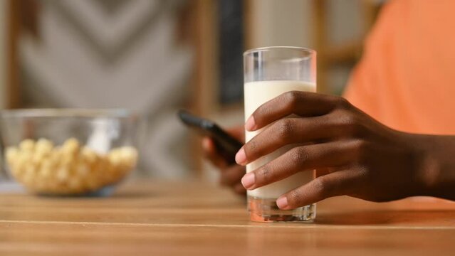 Close-up of a black guy's hand taking a glass of milk from the table and then putting it back