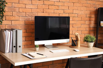 Blank computer monitor with folders on table in office