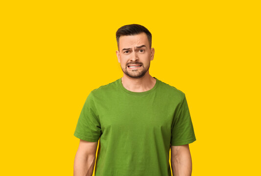 Handsome ashamed young man on yellow background