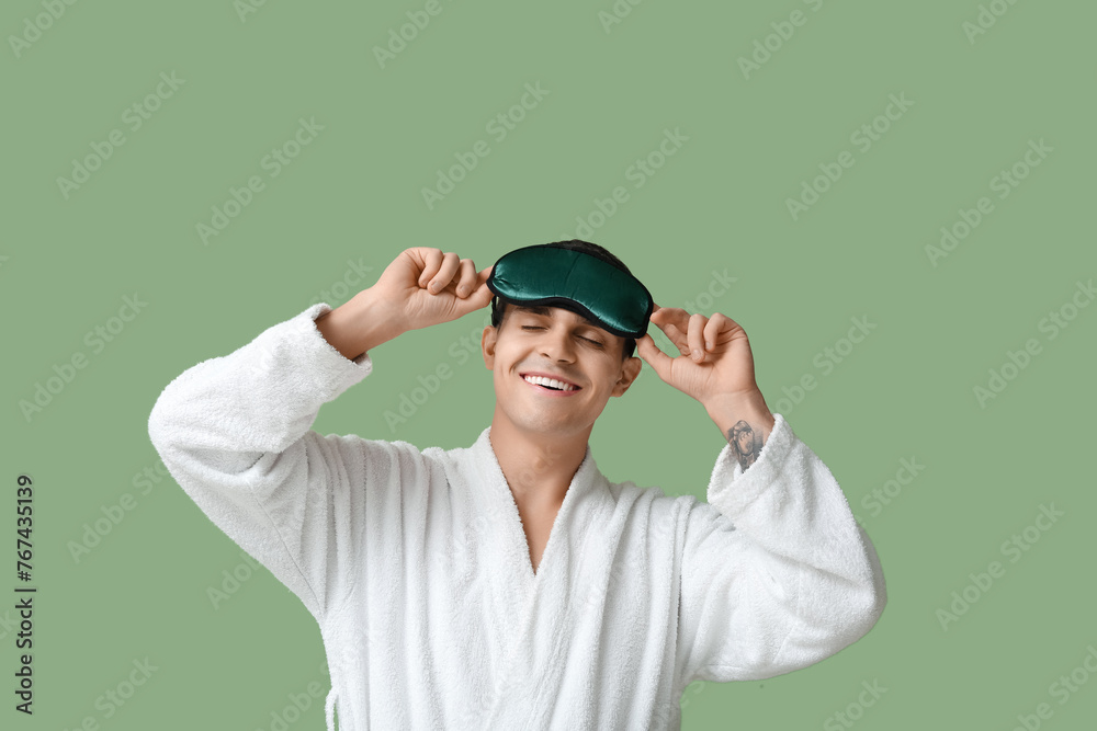 Sticker portrait of handsome young man in bathrobe and sleeping mask on green background