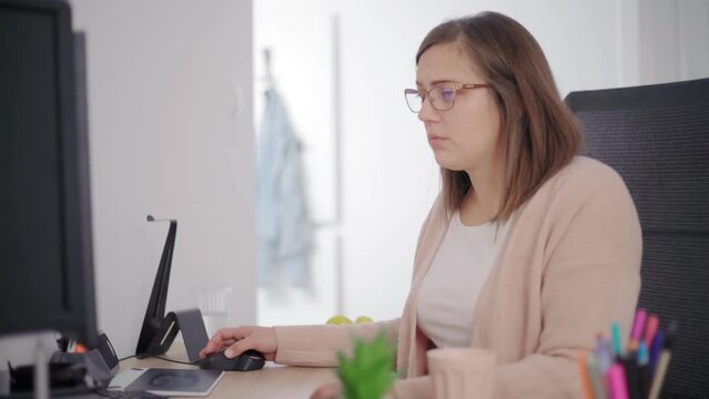 A woman sitting by a computer and working on personal finance at home