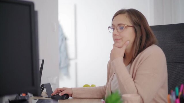 A woman sitting by a computer and working on personal finance at home