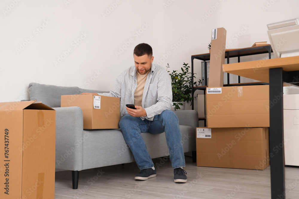 Sticker male seller with parcel and mobile phone sitting in warehouse store