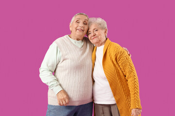 Senior female friends hugging on purple background