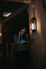 Cheerful female professional engaging with digital tablet in an office setting with intimate, warm lighting.
