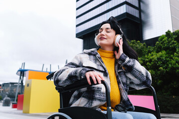 Obraz premium Relaxed Woman in Wheelchair Enjoying Music in Urban Setting