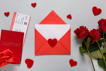 Envelope with blank card, passport, roses and hearts on light background. Valentine's Day celebration