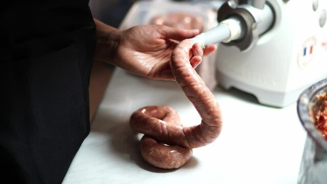 Cook fills the intestine with minced meat on the nozzle of the meat grinder on the table. High quality 4k footage