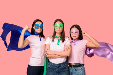 Women in superhero costumes on pink background. Women's history month