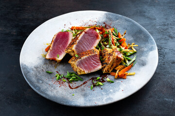 Traditional Japanese gourmet tuna fish steak tataki with vegetable slices and soy sprouts with...