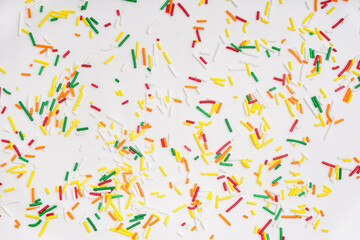 Sweet colorful sprinkles scattered on white background