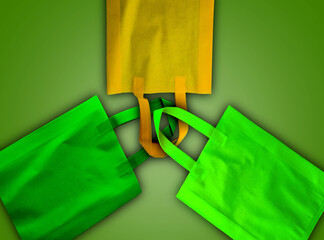 green and yellow polypropylene bags on a soft green background. tote bags of non-woven fabrics