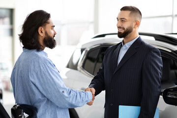 Two men shaking hands in car dealership
