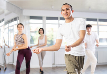 Fototapeta premium Group of happy young people enjoying a contemporary dancing class. Team of smiling dancers in casual wear practising a new choreo