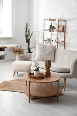 Interior of modern light living room with couch, shelf unit, pouf and table