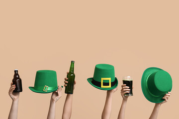 Hands with beer and leprechaun's hats on beige background. St. Patrick's Day celebration