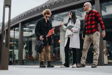 Three entrepreneurs engaged in a conversation while walking outside of a modern office building.
