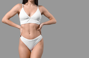 Obraz premium Young woman in white underwear on grey background