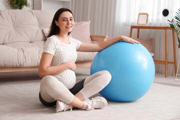 Beautiful young pregnant woman with fitball at home