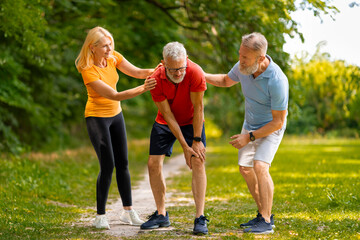 Concerned senior couple helping male friend recover from injury during outdoor training