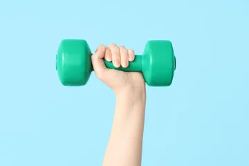 Fotobehang Female hand with dumbbell on color background, closeup © Pixel-Shot