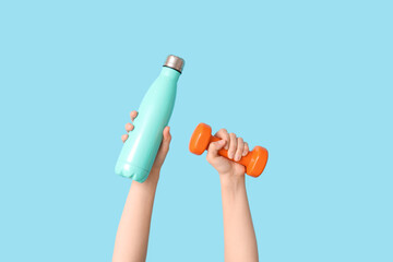 Female hands with dumbbell and bottle of water on color background, closeup