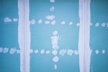 texture of drywall with evenly twisted screws and putty joints in a new renovation made by a...