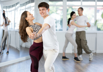 Young man and young woman dance couple latin dances in studio