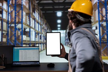 Depot worker examining stock checklist and tablet with white screen, working on delivery and shipment with cargo logistics. Supervisor holding device with blank display copyspace, retail industry.