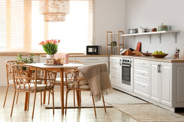 Calendar with date of International Women's Day, tulips and gift on dining table in kitchen