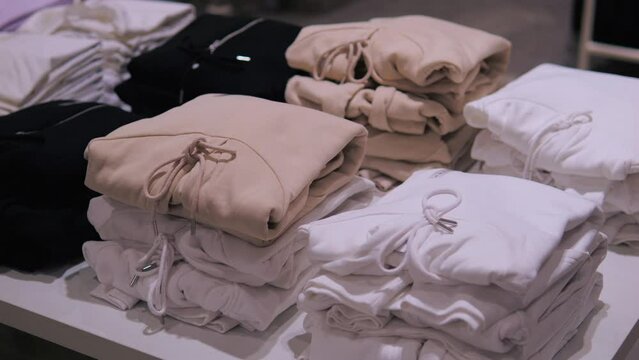 Store stacks of fashionable clothes hoodies and sweaters of different colors. Clothes neatly folded to attract customers attention. Wide range of high-quality clothing allows to choose suitable items.
