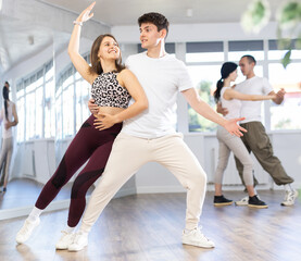Young guy performing kizomba paired with attractive girl in sportswear in choreography studio