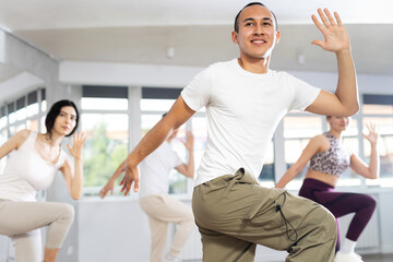 Fototapeta premium Group of young men and women rehearsing hip hop dance in studio