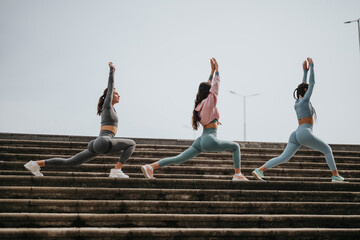 Fitness-focused friends engage in a workout session on steps, demonstrating strength and...
