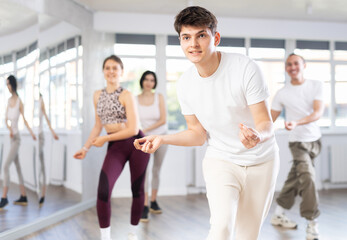 Group of happy young people enjoying a contemporary dancing class. Team of smiling dancers in casual wear practising a new choreo