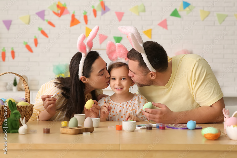 Poster Happy family in bunny ears painting Easter eggs at home