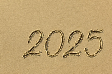 Drawing sun and 2025 on the sandy beach of the coastline as a symbol of the beach season - 767457143