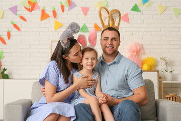 Happy family in Easter bunny ears sitting on sofa at home